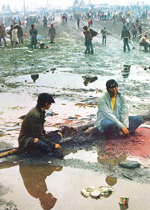 Picture of two guys sitting in mud at Woodstock